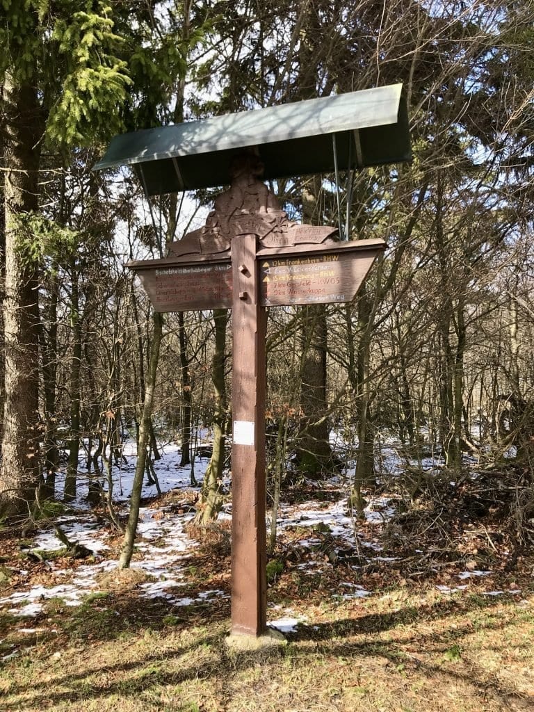 Historischer Wanderwegweiser mit Dach ĂŒber dem Kopf.